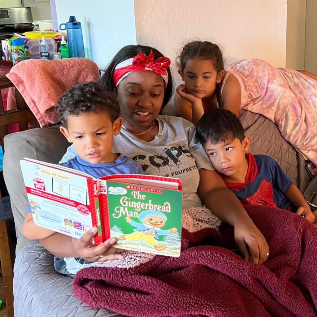 young woman reading to three children