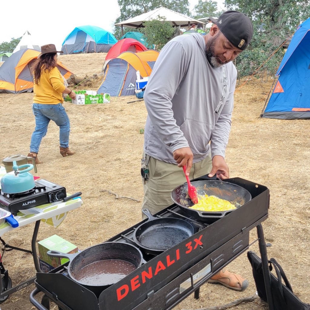 man cooking eggs on outdoor stove