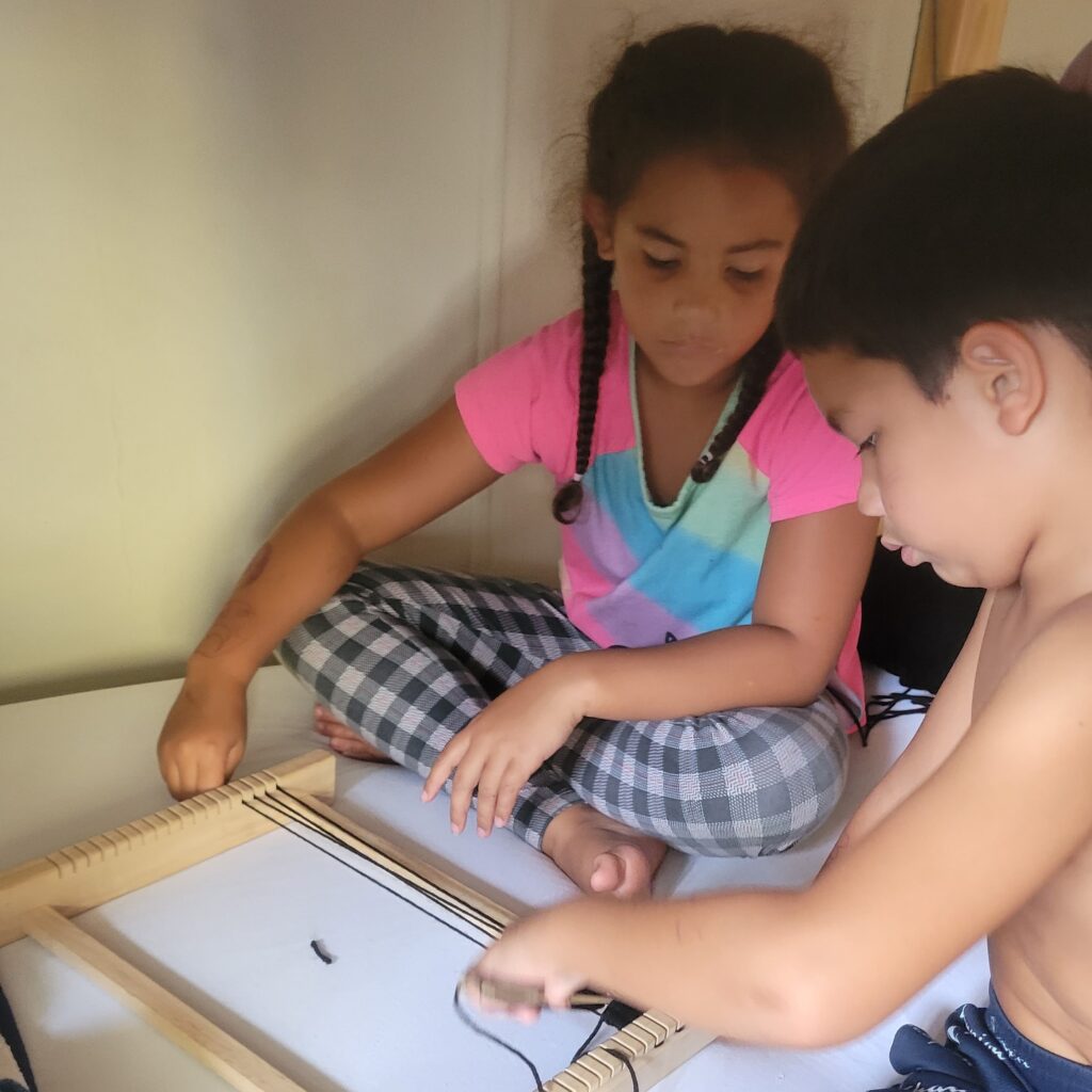 two kids using weaving loom