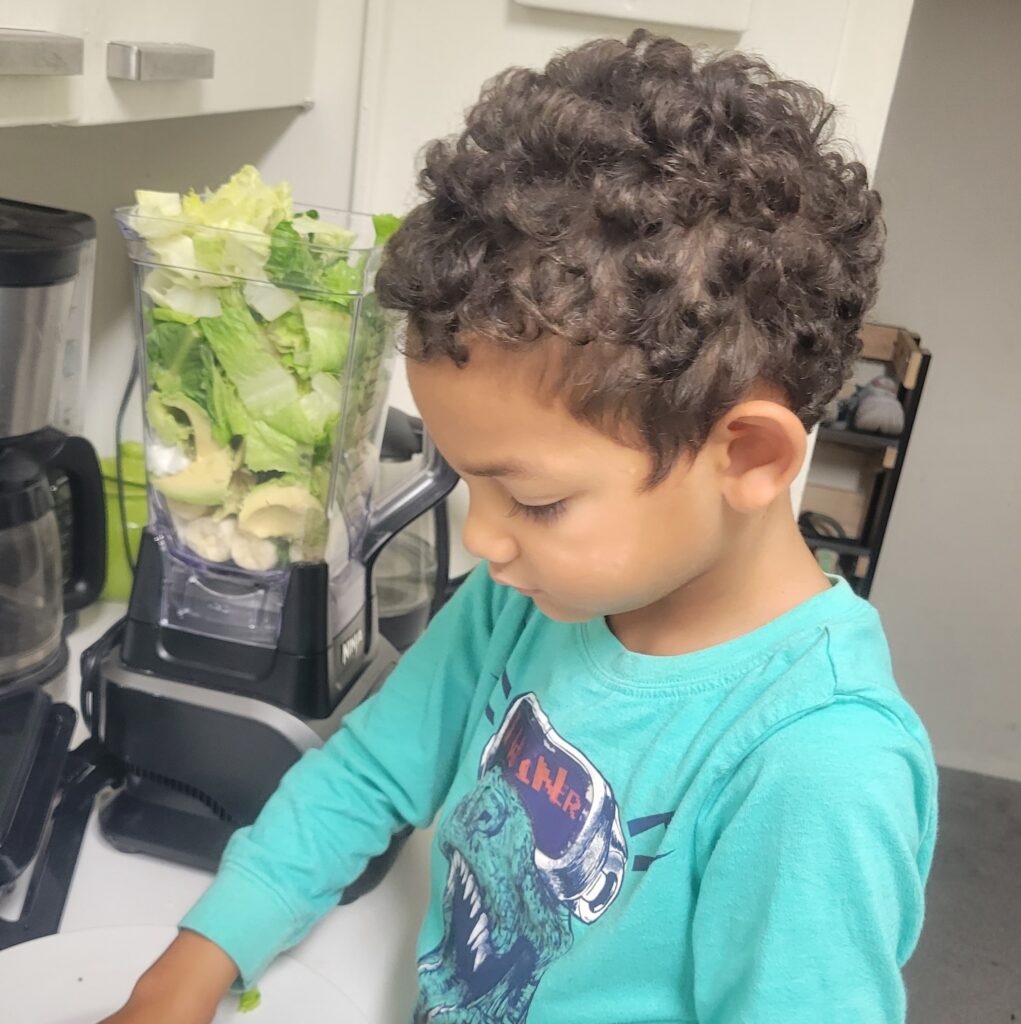 little boy making a green smoothie