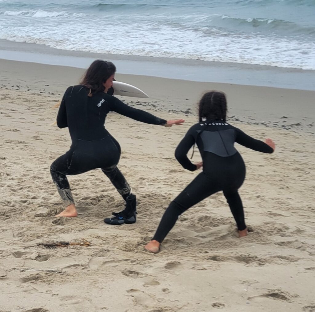two women on beach in wet suits