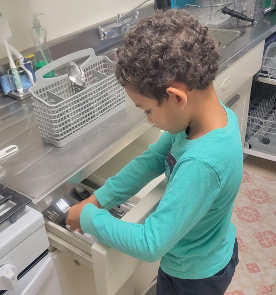 young boy unloading dishwasher