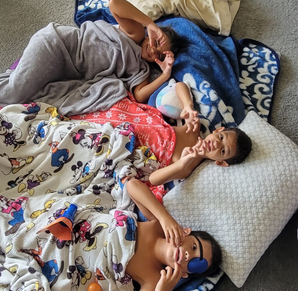 three kids wrapped in blankets on the floor