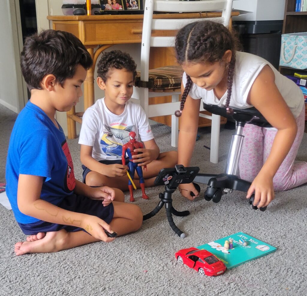 three kids with camera and toys