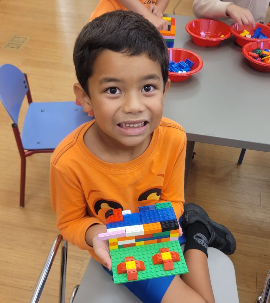 boy in halloween shirt holding lego creation